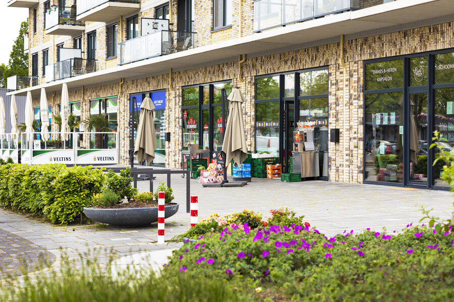 Foto vanaf de straat van plantenbakken en daarachter winkels