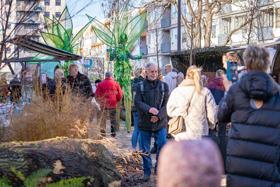 Twee steltlopers in groene pakken met veel mensen erom heen